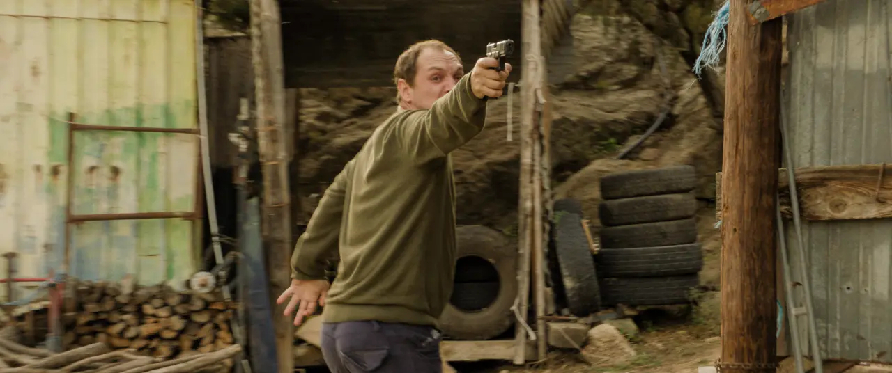 Homem aponta arma em cenário rural em cena de O Último Moicano, entre melhores filmes de ação