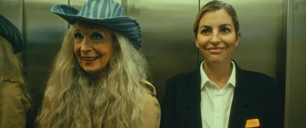 Catarina e hóspede idosa sorriem no elevador em cena de Hotel Amor