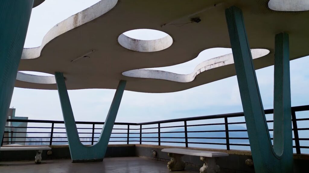Terraço com cobertura curva e pilares azuis em edifício projetado por Artacho Jurado
