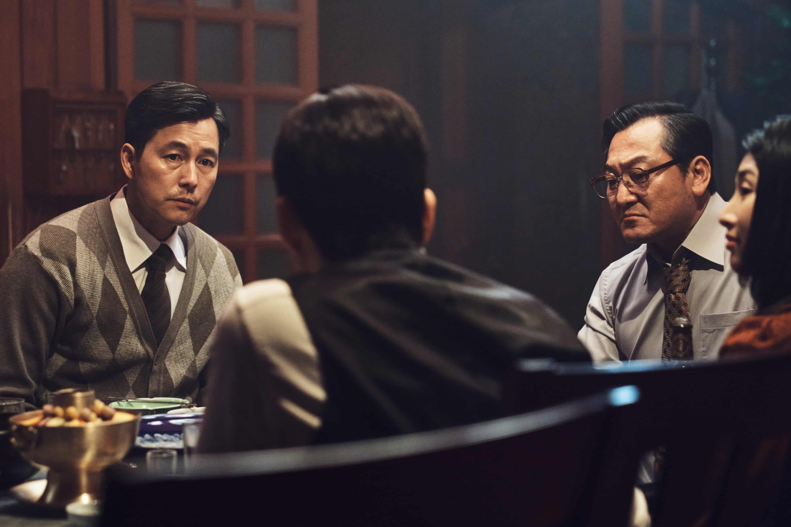 Cena de 12.12: O Dia com homens reunidos à mesa, destaque entre os filmes coreanos