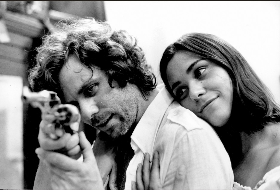 Lúcio Flávio aponta arma ao lado de mulher em cena exibida na Mostra Internacional de Cinema de São Paulo
